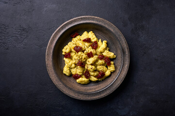 Flat lay Italian potato gnocchi with parmesan and dried tomatoes in rustic plate on a graphite dark background