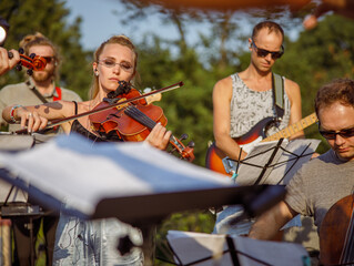 Beautiful woman violinist playing violin in orchestra
