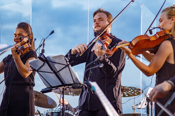 Musical ensemble playing violin against blue sky