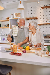 An elderly couple having fun in the kitchen preparing healthy food