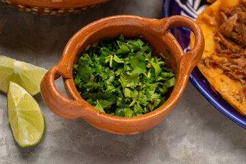 chopped cilantro in an earthenware bowl on a gray background