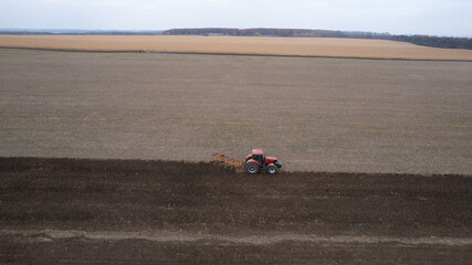 Red Tractor Plowing in Autumn near corn field. Top view from drone