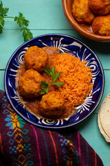 meatballs with red rice and tomato broth on a turquoise background. Mexican food