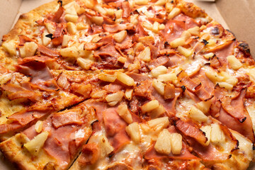 Ham and pineapple pizza called hawaiian on a wooden background