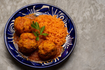 meatballs with red rice and tomato broth on a gray background. Mexican food