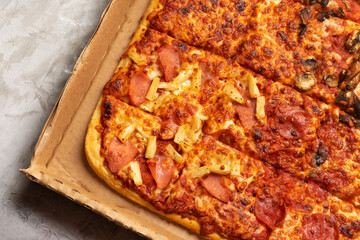 Square pizza inside its box on a gray background