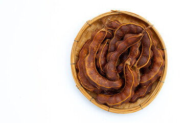 Tamarind tropical fruit in bamboo basket on white background. Top view