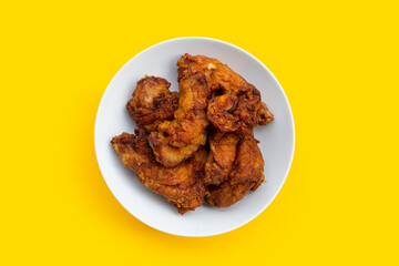 Fried chicken necks in white plate on yellow background.