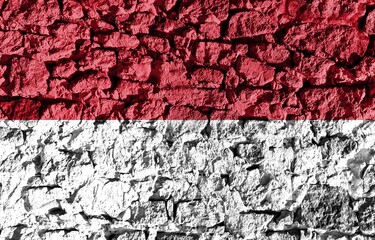 Monaco flag depicted on a stone wall. The texture of the stone blends perfectly with the colors of the banner