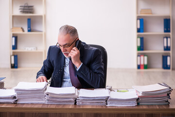 Old businessman employee unhappy with excessive work in the office