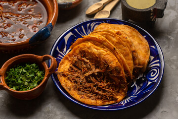 Birria tacos and broth on a gray background. Mexican food