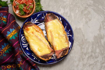 Molletes with ham, refried beans and melted cheese on a gray background. Mexican food