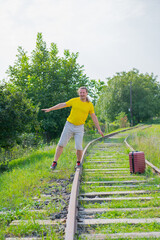 a lone traveler with a red suitcase walks on the rails