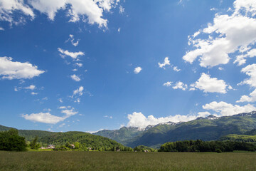 Fototapeta na wymiar Picture of grassfield and agricultural fields and clearing in front of alp mountains in Stara Fuzina, in the Triglav National Park, in Bohinj, in the julian alps in Slovenia, in summer...