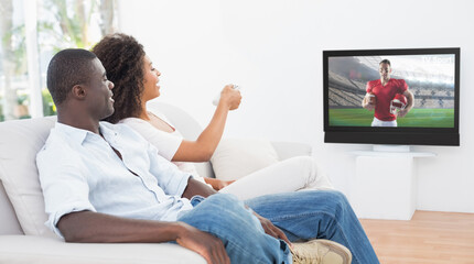 Side view of african american couple sitting at home together watching football match on tv