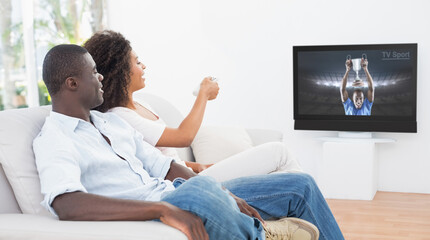 Side view of african american couple sitting at home together watching sport event on tv