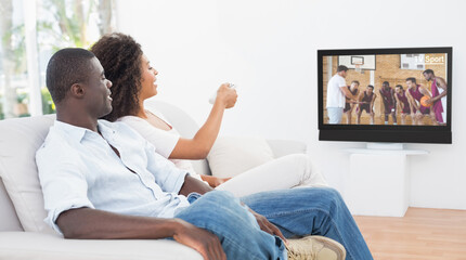 Side view of african american couple sitting at home together watching basketball match on tv