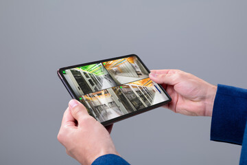 Hands of caucasian man holding tablet with view from security cameras in server room on screen