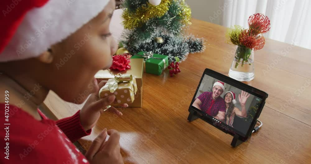 Sticker African american woman with santa hat using tablet for christmas video call with couple on screen