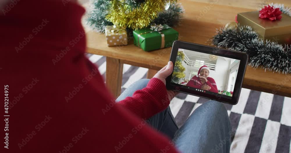 Wall mural Caucasian man waving and using tablet for christmas video call with smiling woman on screen