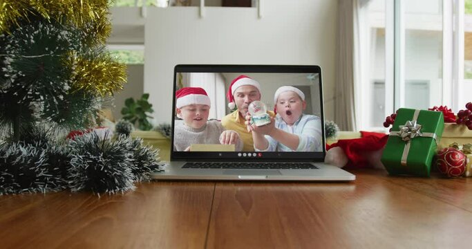 Smiling caucasian family wearing santa hats on christmas video call on laptop
