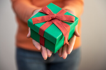 Close-up of a nicely wrapped Christmas gift box in hand. Christmas time concept