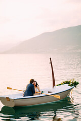 Man kisses woman on the forehead in a boat decorated with flowers in the middle of a pond against a background of mountains