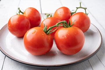 Fresh tomatoes on a green stem on white background
