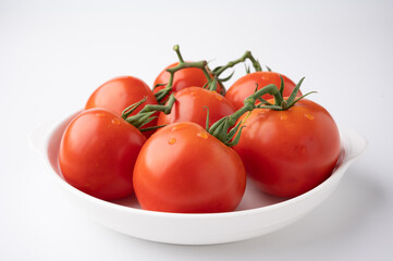 Fresh tomatoes on a green stem on white background
