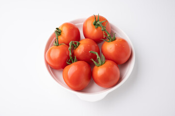 Fresh tomatoes on a green stem on white background