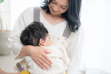 赤ちゃんを白い綺麗な部屋で抱っこする笑顔の美人ママコピースペースあり　アップ