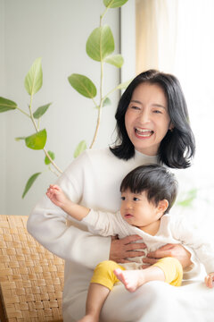 赤ちゃんを白い綺麗な部屋で抱っこするとても幸せそうなママ　コピースペースあり　縦写真	