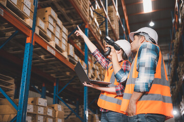 Two logistic staff in safety suite working at warehouse