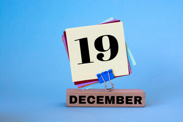 December 19th. Day 19 of December month, calendar on workplace with blue background. Winter time. 