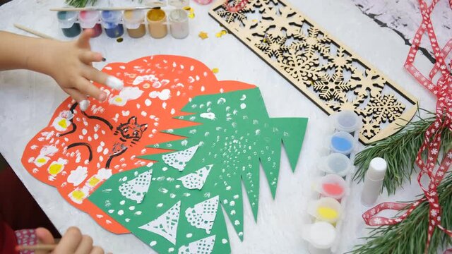 Child making a greeting card  Craft for children. Nice greeting card with a Christmas snowy forest. . Top view