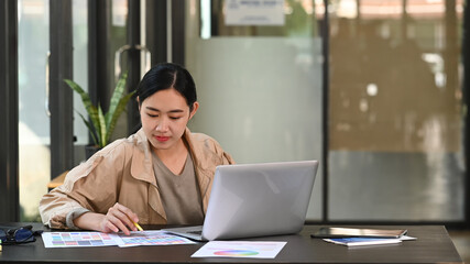 Thoughtful young female designer working in creative office.