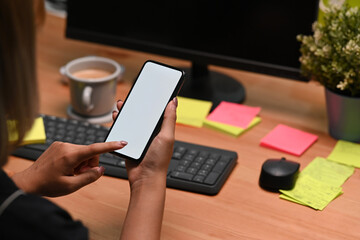 Over shoulder view of asian woman holding mock up smart phone with empty screen.