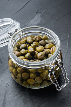 Baby capers in glass jar, on black background
