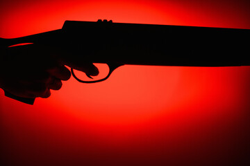 Silhouette of weapons in hands on a red and black background. Part of a rifle. Armed Forces Concept