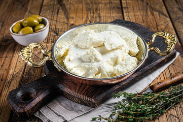 Goat and sheep cheese in a pan with olives and rosemary. Wooden background. Top view