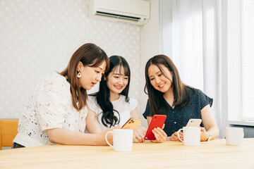 スマホを見る女性たち（テーブル・3人）
