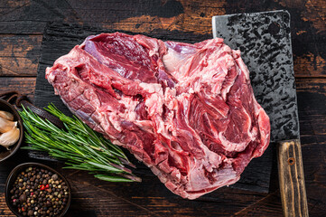 Boneless raw Leg of mutton Lamb meat on butcher cutting board with cleaver. Dark wooden background. Top view