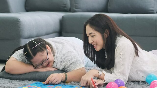 Girl with down syndrome is practicing fun playing with toys at home with his mother.