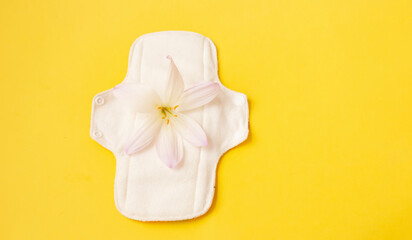Panties and washable sanitary napkins bamboo charcoal pads on yellow background with crocus flower. Sanitary pad for healthy women, reusable menstrual pad. Health care, zero waste, ecological concept.
