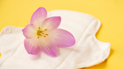 Obraz na płótnie Canvas washable sanitary napkins bamboo charcoal pads on yellow background with crocus flower. Sanitary pad for healthy women, reusable menstrual pad. Health care, zero waste, ecological concept.