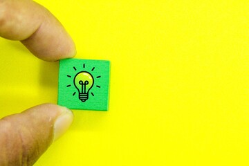 banknotes and hand holding color cubes with bulb icons or concept ideas