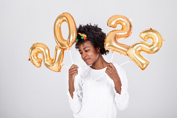 Happy young African American woman holding 2022 gold color balloons for celebrate merry Christmas and happy new year on white background, celebration and decoration for holiday event concept