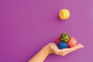 Variously colored colorful embroidery threads in hand on a purple background