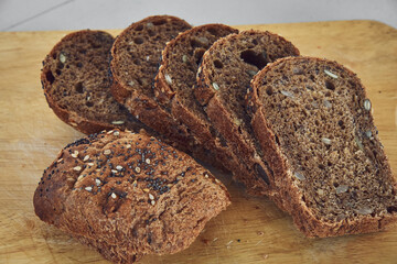 Sliced rye bread with sunflower and poppy seeds on rustic wooden background. Healthy food still life