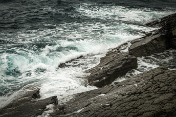 sea waves with splashes and foam wash over the rocky stones